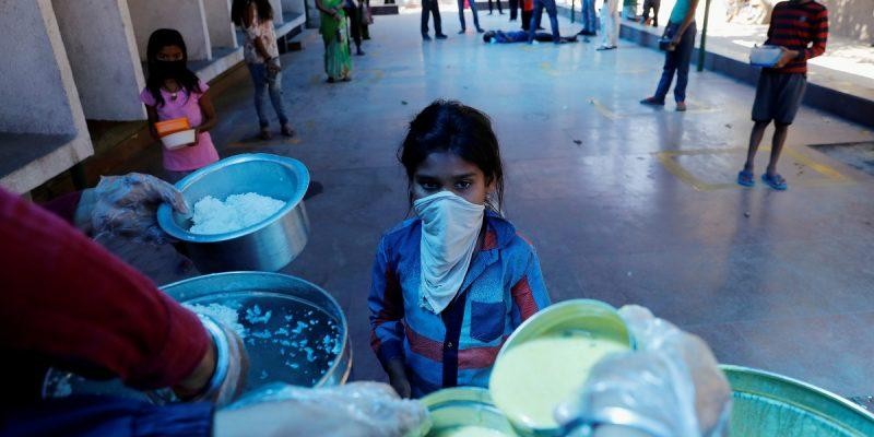 A child wearing a mask waits to receive free food being distributed by the Delhi government in a school to poor people in Ghaziabad, on the outskirts of New Delhi. Photo: REUTERS